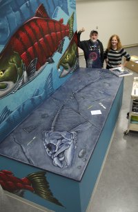Ray Troll and Liz White stand at a mural project they did together