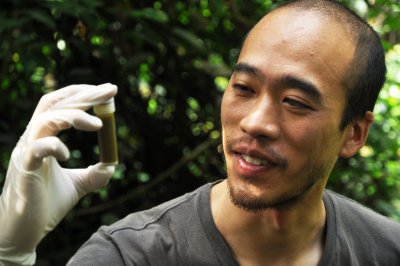 Nelson Ting holds a fecal sample in vial on location in Africa