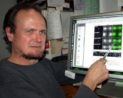 UO biologist Bruce Bowerman points to images showing cell division  (Photo by Jim Barlow)