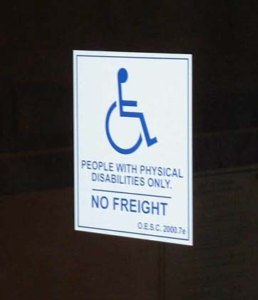 Sign on wheelchair lift:  wheelchair symbol, "people with physical disabilities only, NO FREIGHT"